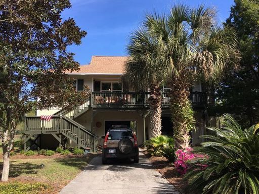 An image of the house hidden behind the tree and a car below at 412 West Indian Ave Folly Beach, SC 29439