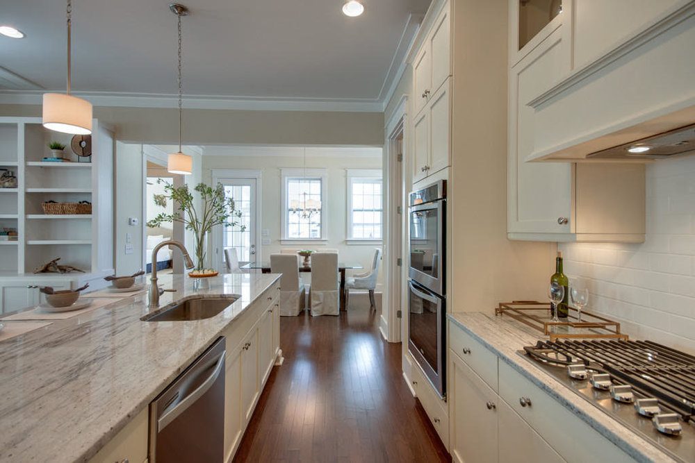 A well organised kitchen with white cabinets and dining table