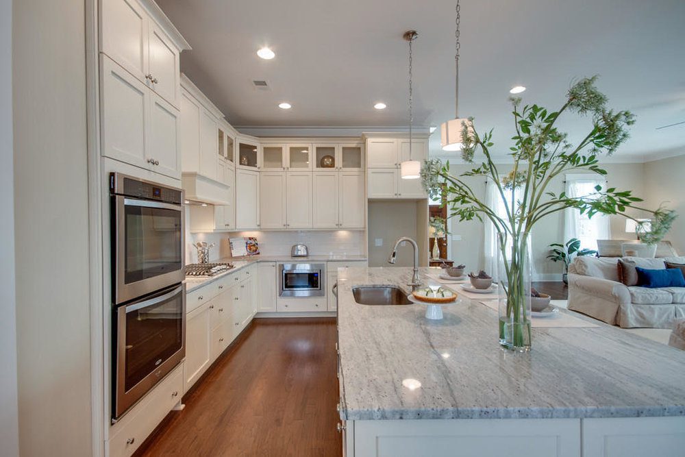 A well organised kitchen with white cabinets and dining table