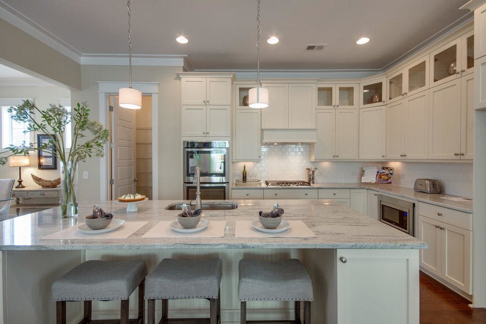 A well organised kitchen with white cabinets and dining table