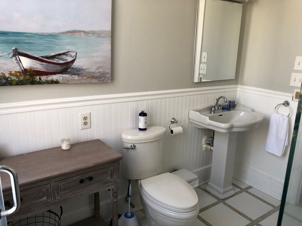 An inside image of the restroom with boat painting above the toilet seat