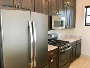 An image of kitchen with black coloured refrigerator and cabinets in side of it