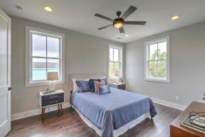 A furnished bedroom with purple bed and fan rotating above it