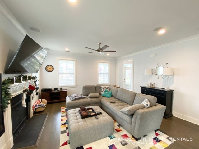 An inside image of a well furnished living room with hanging tv above the fireplace