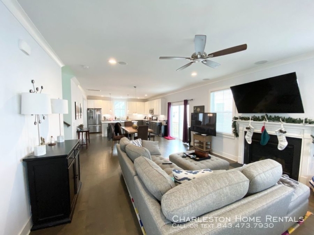 An inside image of a well furnished living room with hanging tv above the fireplace