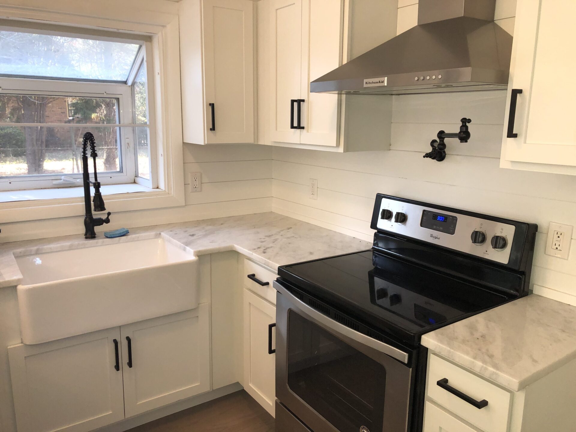 An inside image of the kitchen with white cabinets and black stove