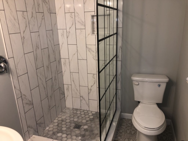 A shower booth and a toilet seat next to it