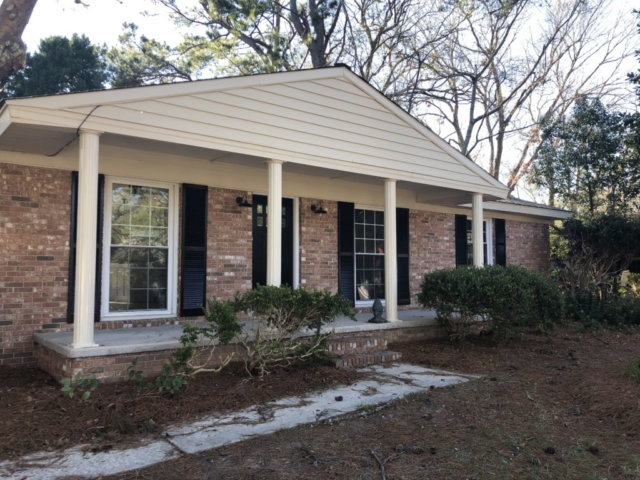 An image of the one story house with green grass in front of it