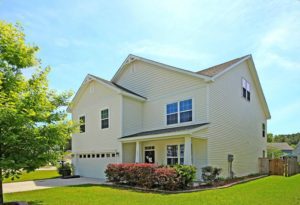 A two story yellow coloured house with bushes in front and large lawn at Wapiti Way Hollywood, SC 29449