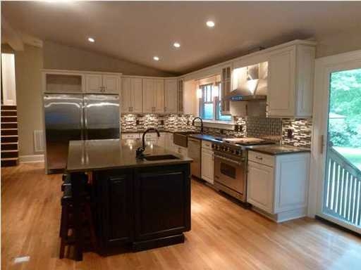 An image of well lightened kitchen with brown square dining table