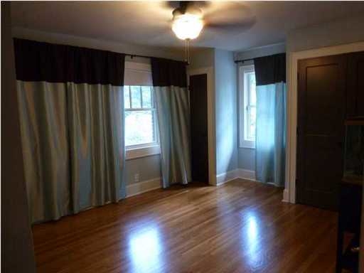 An image of an empty room with just curtains on the window